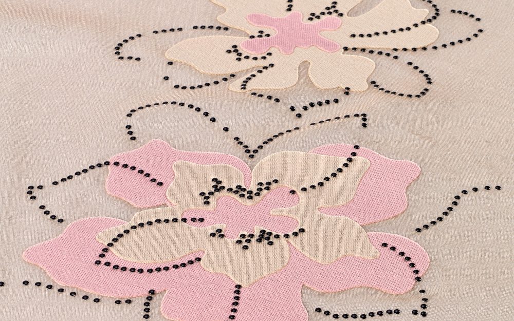 Decorazione floreale realizzata con la sovrapposizione di tessuti e borchie termoadesive