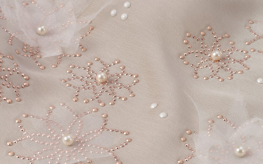 Decorazione floreale su tessuto con perle, borchiette e tulle